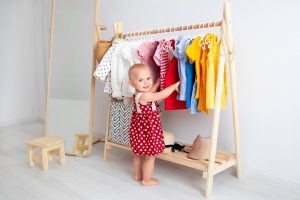 Baby,girl,stands,near,a,wardrobe,and,chooses,a,dress