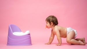 Cute,baby,in,a,diaper,sitting,on,a,potty.,toilet