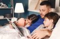 Father,reading,bedtime,story,to,his,little,children,at,home
