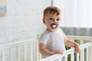 Cute,little,baby,boy,with,pacifier,in,baby,crib,looking